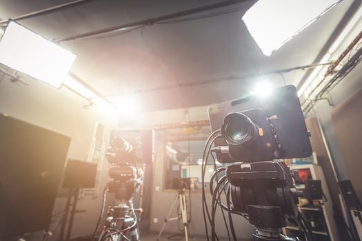 Film camera on a tripod in a television broadcasting studio, spotlights and equipment