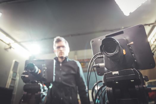 Male cameraman is operating a film camera in a television recording studio