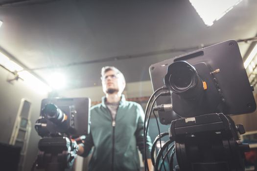 Male cameraman is operating a film camera in a television recording studio