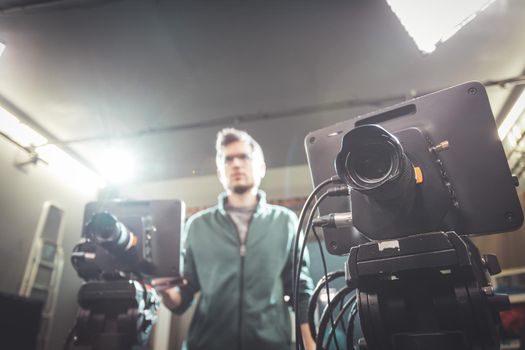 Male cameraman is operating a film camera in a television recording studio