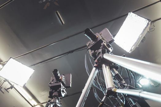 Film camera on a tripod in a television broadcasting studio, spotlights and equipment