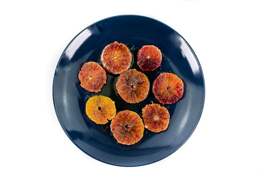 oranges seasoned with oil salt and pepper on a blue plate white background