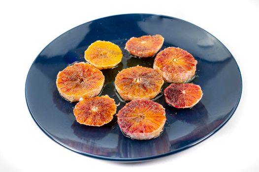 oranges seasoned with oil salt and pepper on a blue plate white background