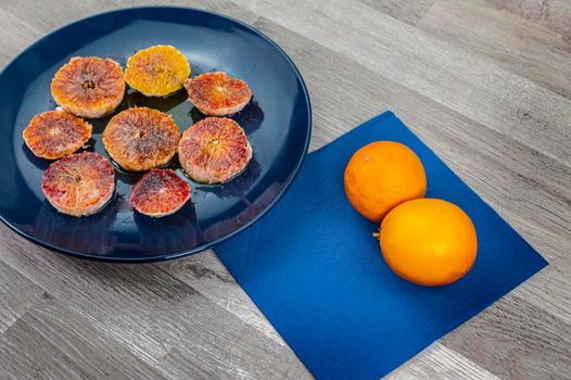 oranges seasoned with oil salt and pepper on a blue plate and wooden background oranges