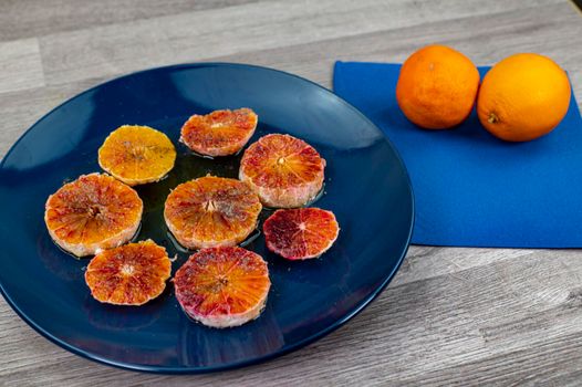 oranges seasoned with oil salt and pepper on a blue plate and wooden background oranges