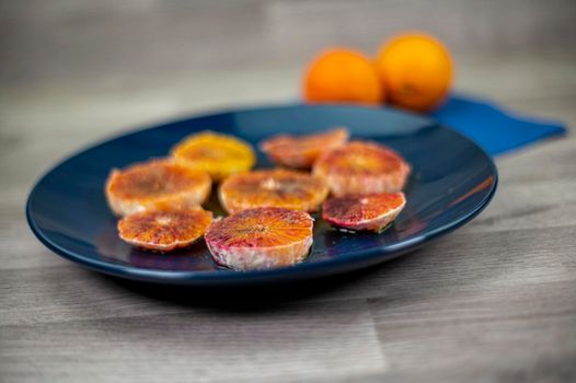 oranges seasoned with oil salt and pepper on a blue plate and wooden background oranges