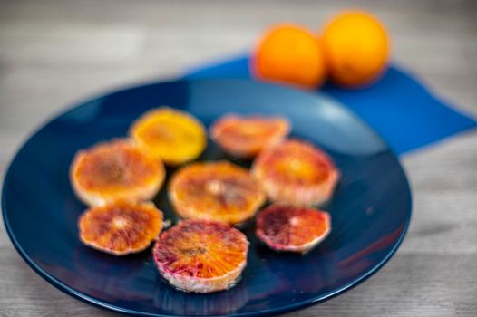 oranges seasoned with oil salt and pepper on a blue plate and wooden background oranges