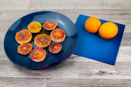 oranges seasoned with oil salt and pepper on a blue plate and wooden background oranges
