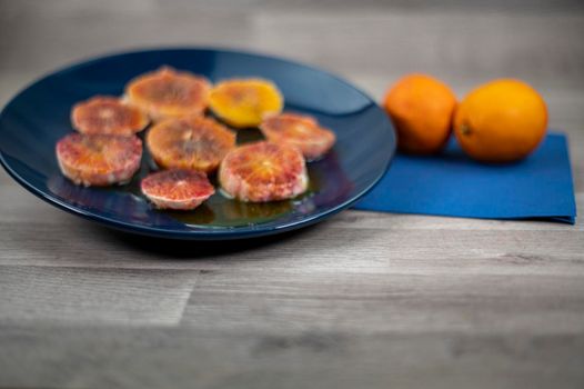 oranges seasoned with oil salt and pepper on a blue plate and wooden background oranges