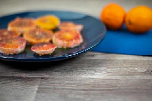 oranges seasoned with oil salt and pepper on a blue plate and wooden background oranges