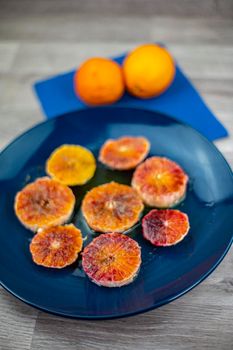 oranges seasoned with oil salt and pepper on a blue plate and wooden background oranges