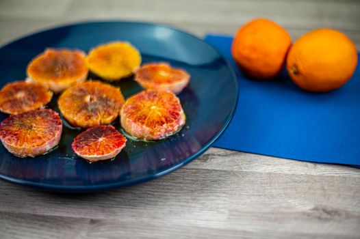 oranges seasoned with oil salt and pepper on a blue plate and wooden background oranges