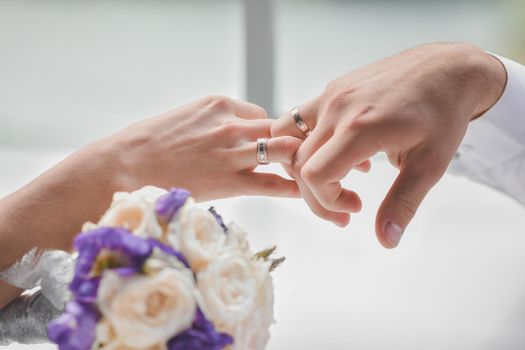 A woman and a man hold each other's hands. In the hands of an engagement ring. The man proposed to his woman and gave her a bouquet of flowers. Without face. Selective defocusing