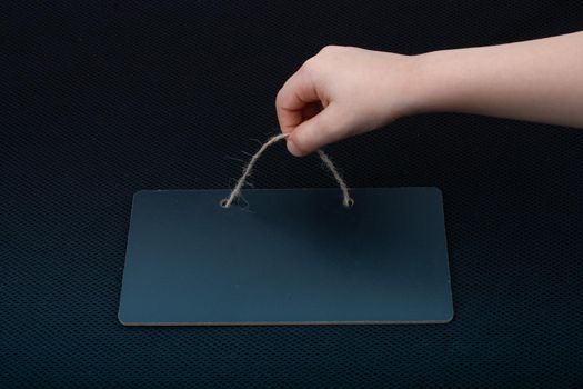 Rectangular shaped black notice board in hand on black background