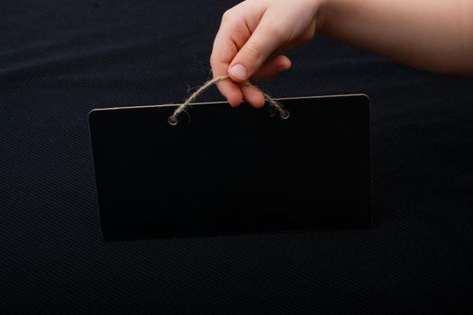 Rectangular shaped black notice board in hand on black background