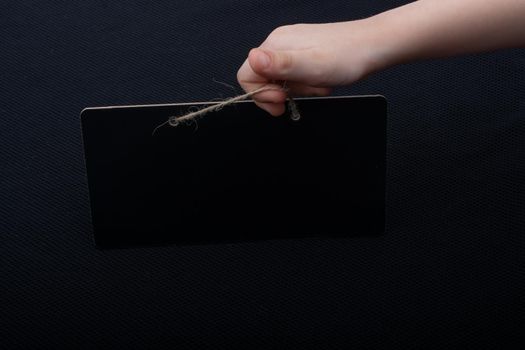 Rectangular shaped black notice board in hand on black background