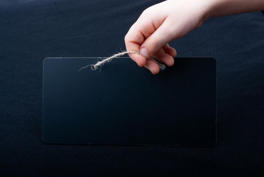 Rectangular shaped black notice board in hand on black background