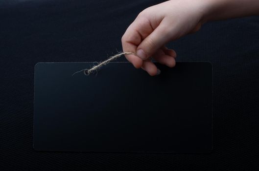 Rectangular shaped black notice board in hand on black background