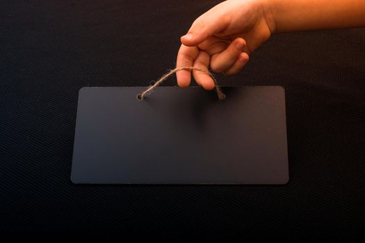 Rectangular shaped black notice board in hand on black background