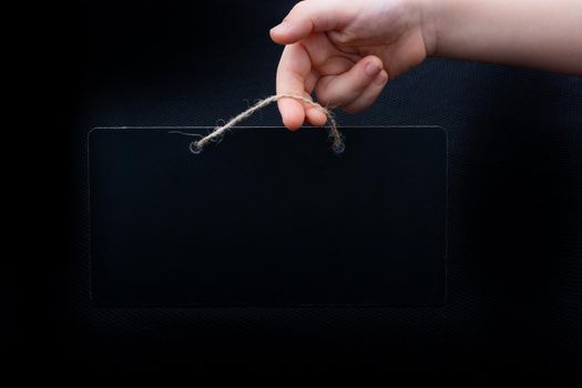 Rectangular shaped black notice board in hand on black background