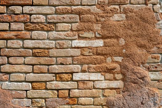 Background from a red rough brick wall with the remains of some plaster