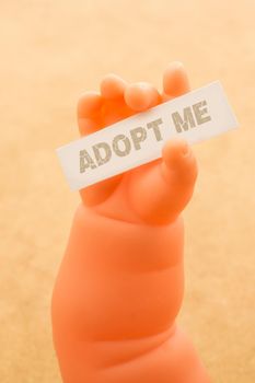 Toy doll hand holding paper with ADOPT ME wording