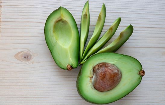 Slices of ripe avocado lie on a light cutting board.