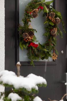 Detail of a Christmas wreath in a black door in a snowy day