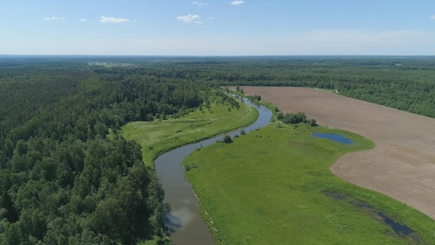 Aerial view summer landscape, river among trees, farmlands. Countryside with forest, the banks river covered with greenery.