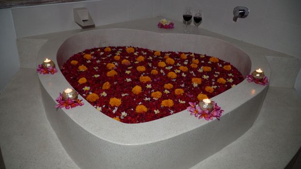 heart shaped bath with petals tropical flowers. Luxury spa. Rest body and soul.Beauty Style. Romantic gift for Valentine's Day.