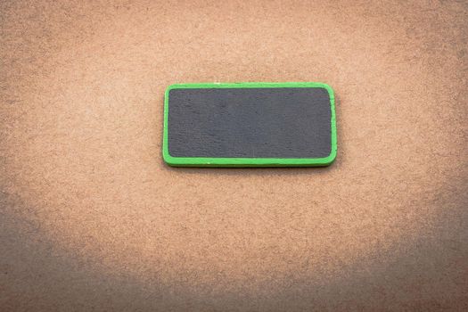 Small green sided black noticeboard on a wooden background