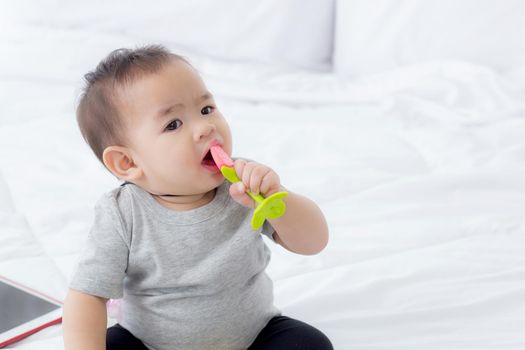 Portrait of cute little baby girl sitting with cozy on bed at bedroom, happiness of toddler, newborn 6-11 months with innocence and expression with cheerful, child charm, indoors, one person.