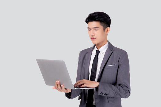 Young asian business man standing work on laptop computer to internet online isolated on white background, businessman confident and notebook, freelance with success, marketing and communication.