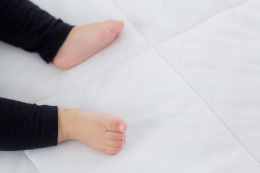 Closeup foot of asian little baby girl sleeping on bed in the bedroom at home, newborn napping with cozy and relax, infant innocence in bedtime, happy toddler cute, growth of child and emotion.