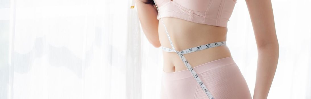 Beautiful young asian woman sexy body slim measuring abdomen for control weight loss in the room, beauty girl belly thin have cellulite with tape measure for diet, health concept, banner website.