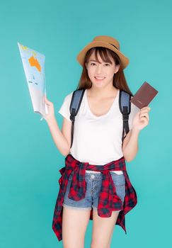 Beautiful happy young asian woman travel holding passport and looking a paper map isolated on blue background, asia girl search journey with direction in vacation trip with cheerful for leisure.