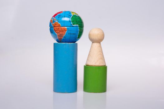 Wooden figurines of people aand a mini globe on white background