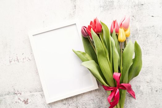 Spring concept. colorfull tulip bouquet and blank frame for mock up design on white background with copy space
