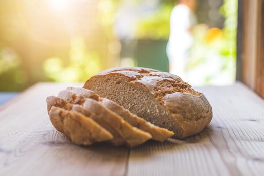 Fresh dark bread in slices, lying on a wooden cutting board. Defocused, blurry background
