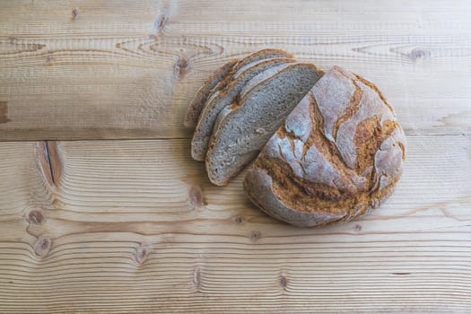 Fresh dark bread in slices, lying on a wooden cutting board.