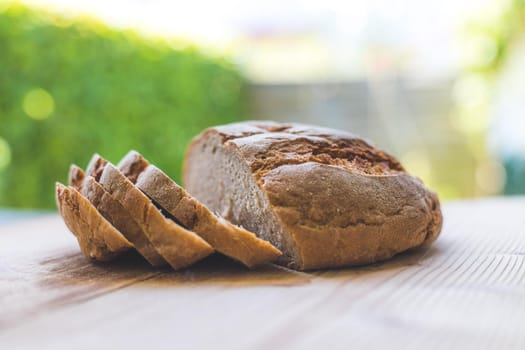 Fresh dark bread in slices, lying on a wooden cutting board. Defocused, blurry background