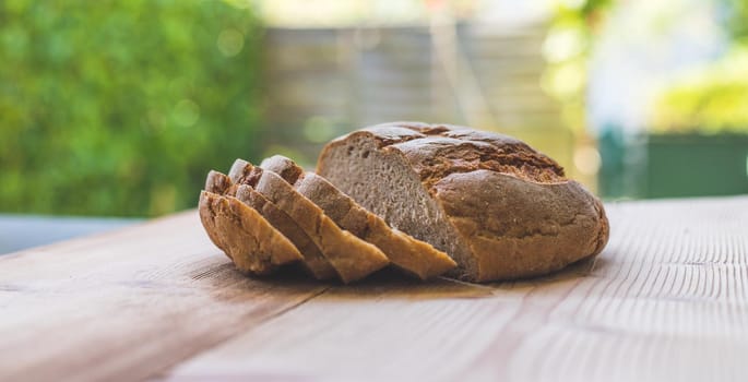 Fresh dark bread in slices, lying on a wooden cutting board. Defocused, blurry background