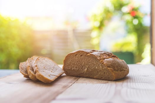 Fresh dark bread in slices, lying on a wooden cutting board. Defocused, blurry background