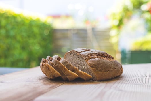Fresh dark bread in slices, lying on a wooden cutting board. Defocused, blurry background