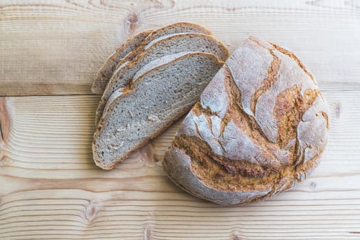 Fresh dark bread in slices, lying on a wooden cutting board.