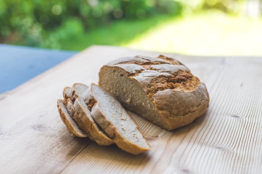 Fresh dark bread in slices, lying on a wooden cutting board. Defocused, blurry background