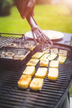 Close up of cheese and vegetables on gas grill. Summer time, outdoors.