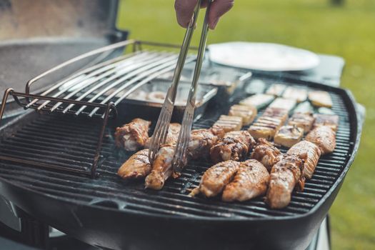 Close up of chicken wings, cheese and vegetables on gas grill. Summer time, outdoors.