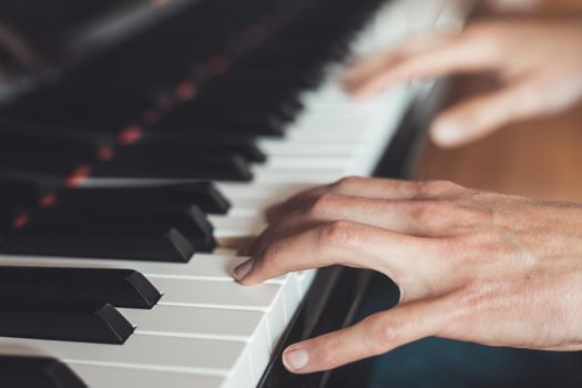 Man is playing piano at home. Clipping of piano and hands.