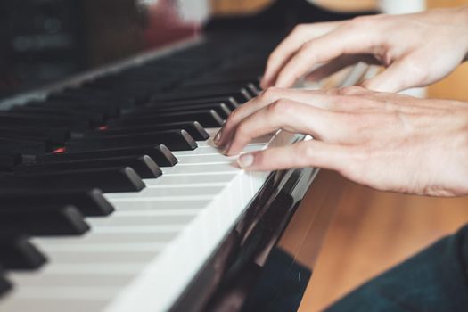 Man is playing piano at home. Clipping of piano and hands.